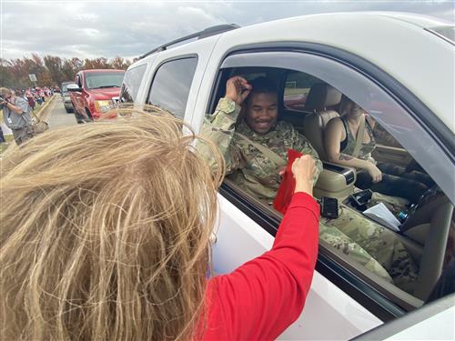 Teacher handing over gift bag to veteran in the drive through line 